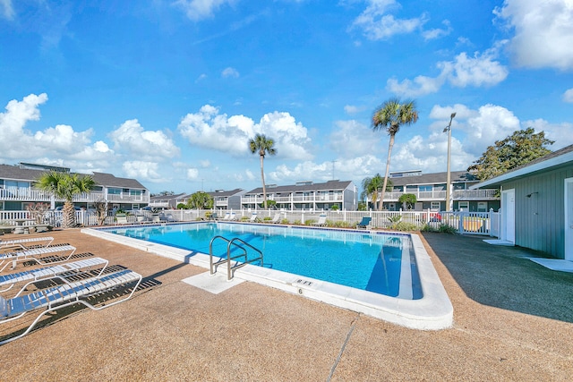 community pool featuring a residential view, fence, and a patio