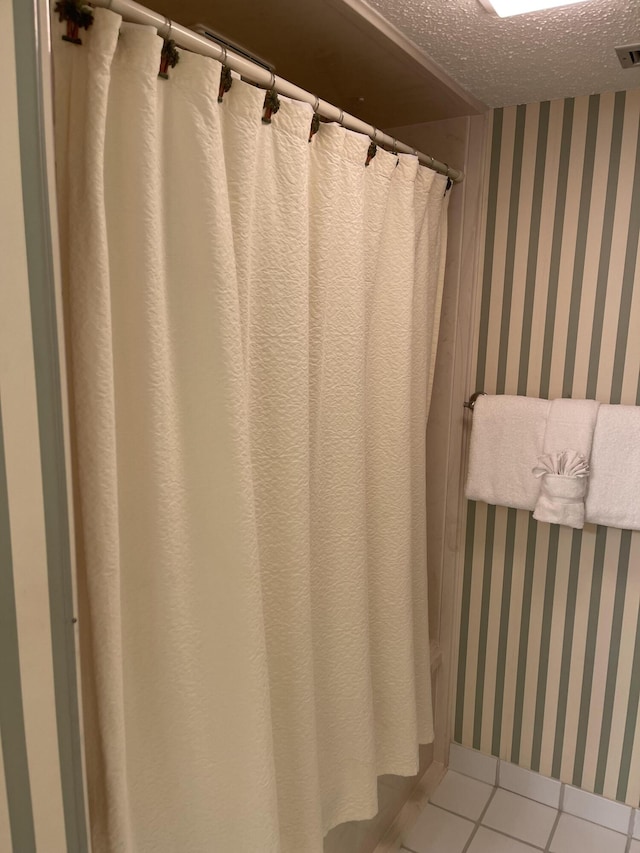 bathroom with tile patterned flooring and a textured ceiling