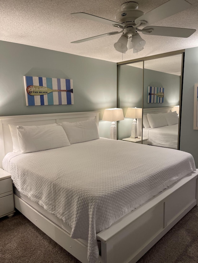 bedroom featuring dark colored carpet, ceiling fan, and a textured ceiling