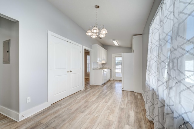 interior space with an inviting chandelier, white cabinets, white refrigerator, hanging light fixtures, and light hardwood / wood-style floors