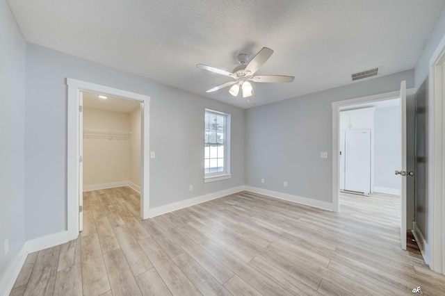 spare room with ceiling fan, light hardwood / wood-style floors, and a textured ceiling