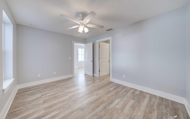 spare room featuring ceiling fan, light hardwood / wood-style floors, and a textured ceiling