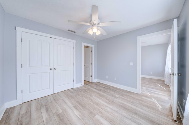 unfurnished bedroom featuring ceiling fan, light hardwood / wood-style floors, and a closet