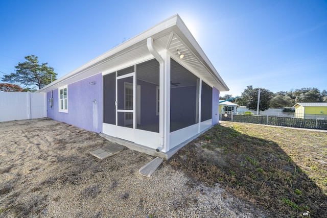 view of side of home with a sunroom and a lawn