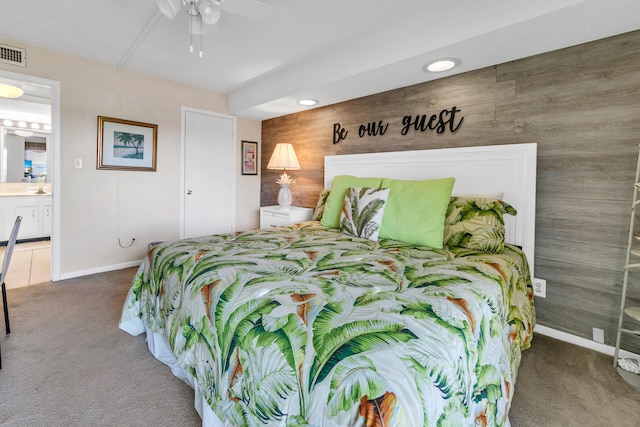 bedroom featuring ceiling fan, dark carpet, and ensuite bathroom