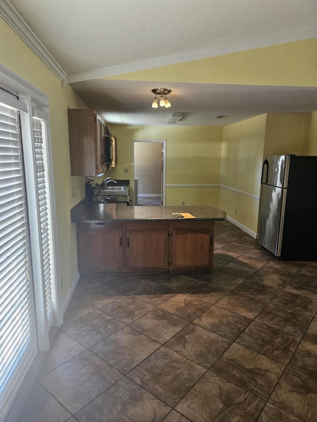 kitchen with stainless steel refrigerator, crown molding, kitchen peninsula, and lofted ceiling