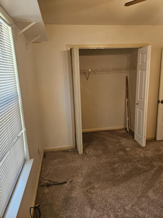 unfurnished bedroom featuring carpet, ceiling fan, and a closet