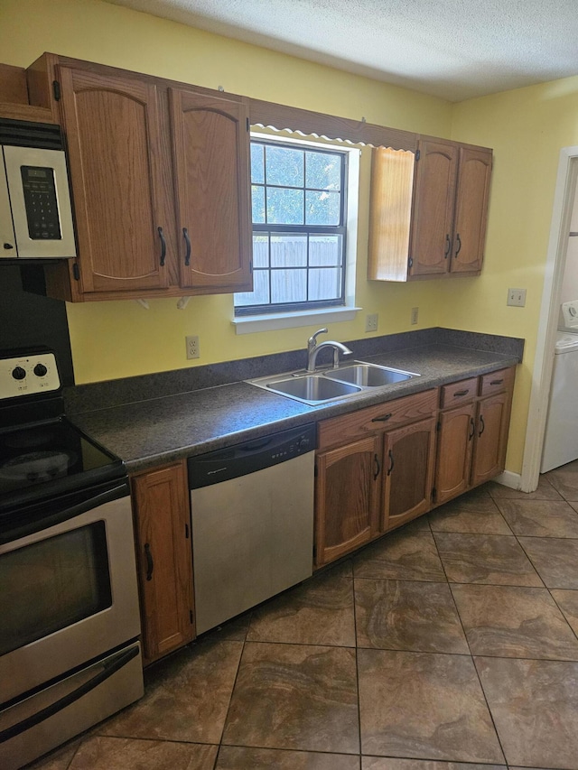 kitchen featuring sink, washer / dryer, dark tile patterned floors, and stainless steel appliances