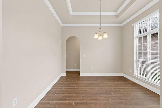 spare room with a tray ceiling, a chandelier, and ornamental molding