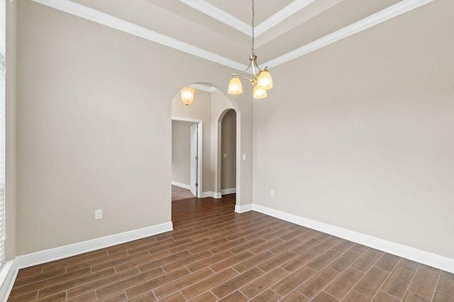 spare room featuring a raised ceiling, an inviting chandelier, and ornamental molding