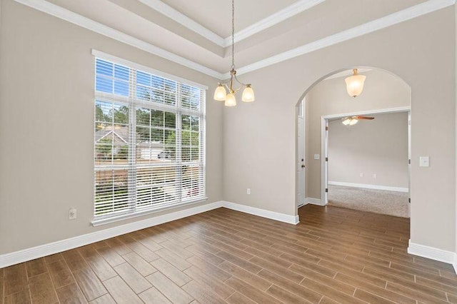 spare room featuring wood-type flooring, ceiling fan with notable chandelier, a tray ceiling, and ornamental molding