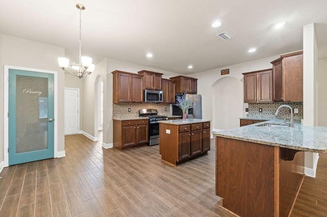 kitchen featuring a breakfast bar, sink, decorative light fixtures, kitchen peninsula, and stainless steel appliances