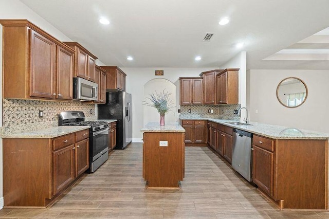 kitchen featuring a kitchen island, light stone counters, kitchen peninsula, and appliances with stainless steel finishes