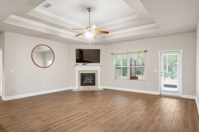 unfurnished living room featuring a tray ceiling, a tile fireplace, ceiling fan, and dark wood-type flooring