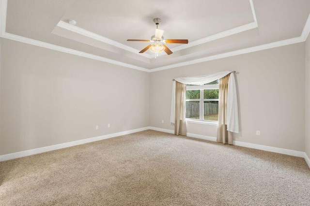 carpeted spare room featuring a raised ceiling, ceiling fan, and crown molding