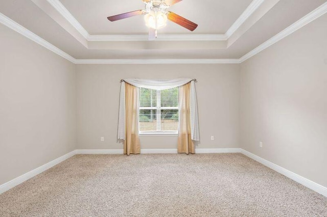 carpeted spare room with ceiling fan, crown molding, and a tray ceiling