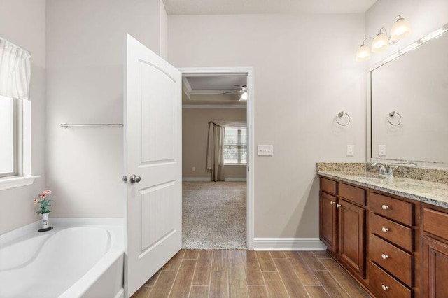 bathroom featuring vanity, a tub to relax in, and ceiling fan