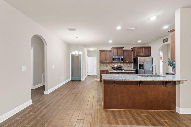 kitchen featuring sink, stainless steel appliances, kitchen peninsula, decorative backsplash, and a breakfast bar