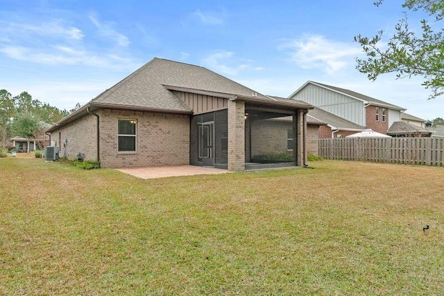 back of property with central AC, a patio area, and a lawn