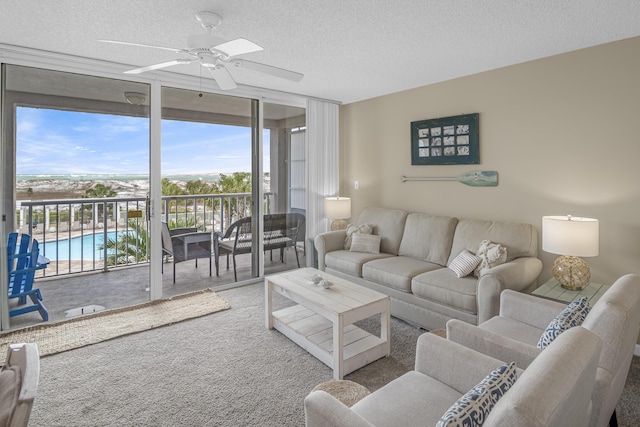 living room with carpet flooring, ceiling fan, floor to ceiling windows, and a textured ceiling