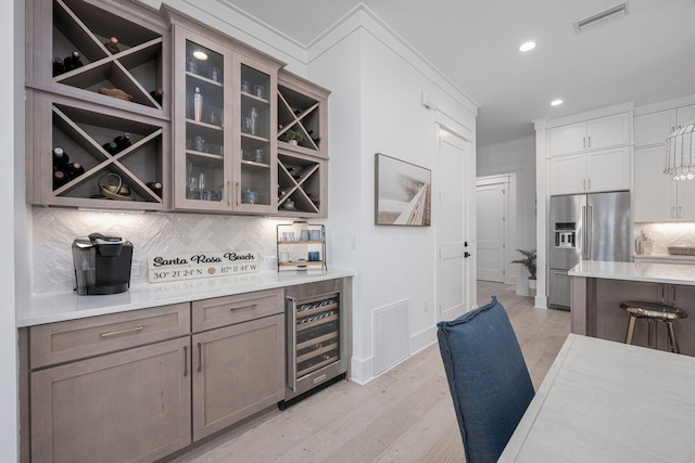 kitchen featuring wine cooler, tasteful backsplash, ornamental molding, light hardwood / wood-style floors, and high end refrigerator