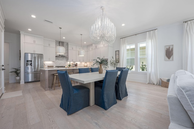 dining room with light hardwood / wood-style floors and an inviting chandelier