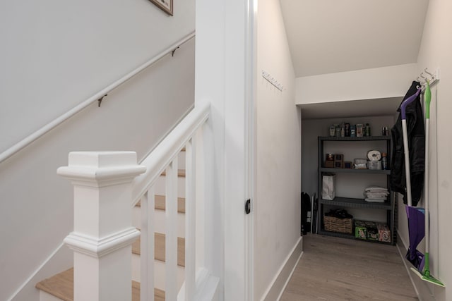 stairway featuring hardwood / wood-style floors and vaulted ceiling