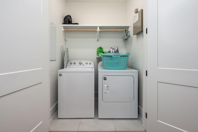 clothes washing area featuring light tile patterned floors and washing machine and dryer