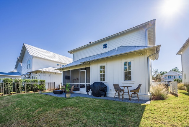 back of property with a sunroom, a yard, and a patio area