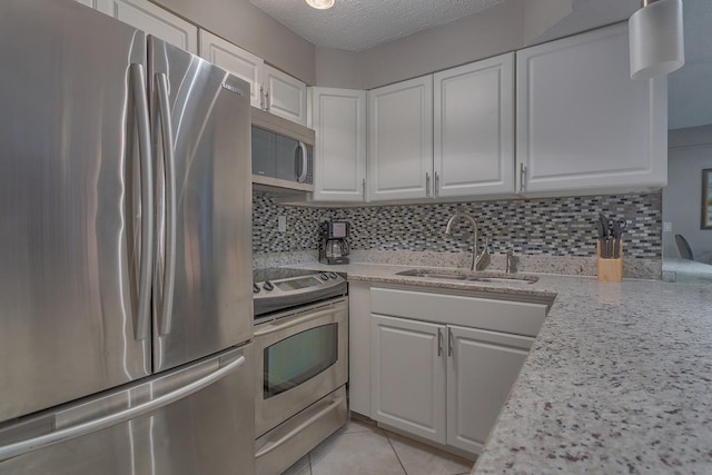 kitchen with tasteful backsplash, sink, white cabinets, and appliances with stainless steel finishes