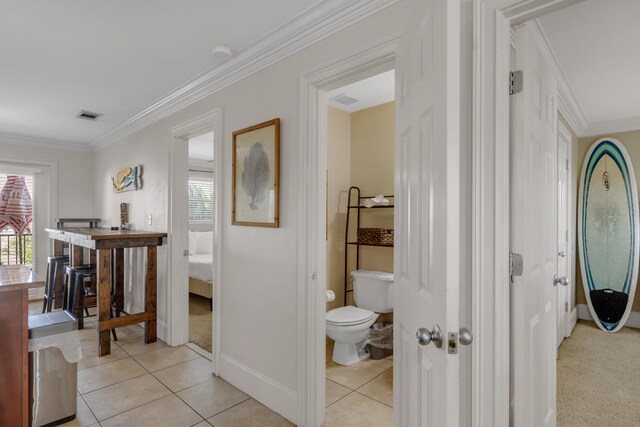 corridor with light tile patterned floors and crown molding