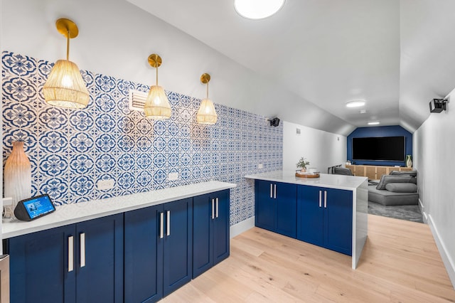 kitchen with lofted ceiling, blue cabinets, pendant lighting, and light hardwood / wood-style floors