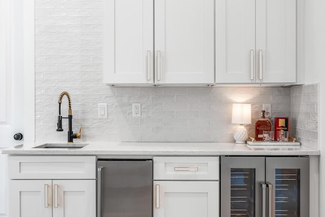 bar with wine cooler, sink, white cabinetry, and stainless steel refrigerator