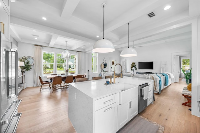 kitchen featuring light stone countertops, a kitchen island with sink, pendant lighting, and white cabinets