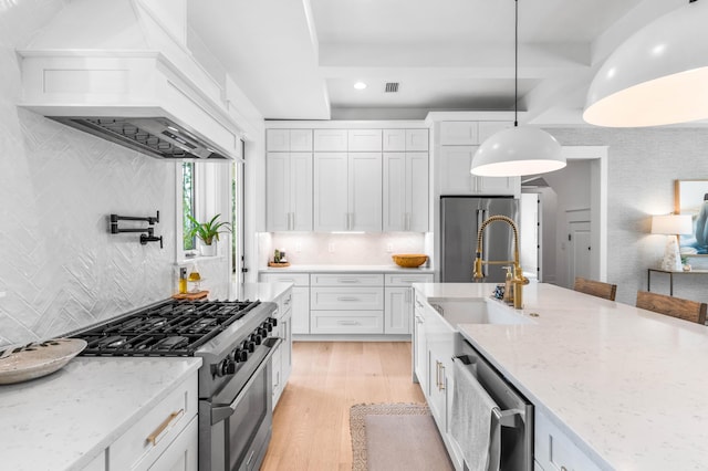 kitchen featuring white cabinets, appliances with stainless steel finishes, custom exhaust hood, and hanging light fixtures