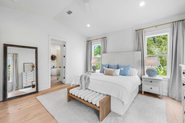 bedroom featuring lofted ceiling, connected bathroom, and light hardwood / wood-style flooring