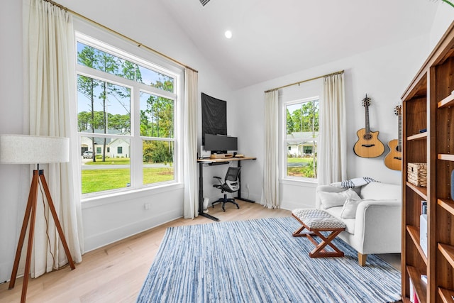 living area featuring vaulted ceiling, a healthy amount of sunlight, and light hardwood / wood-style floors