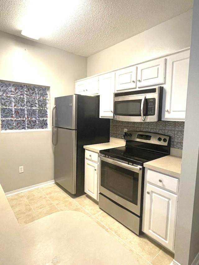 kitchen featuring backsplash, white cabinetry, light tile patterned floors, and stainless steel appliances