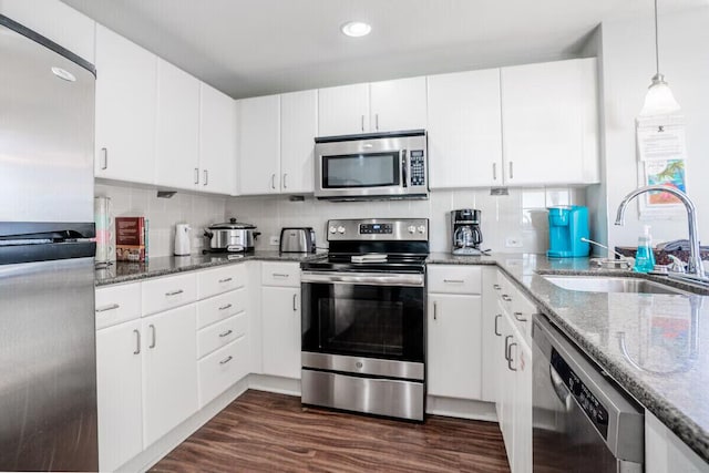 kitchen with white cabinets, appliances with stainless steel finishes, dark stone counters, and sink