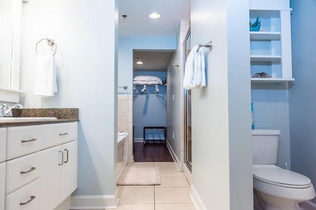 bathroom featuring tile patterned flooring, vanity, a shower with shower door, and toilet