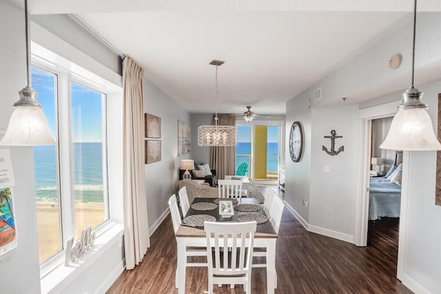 dining area featuring ceiling fan, a water view, and dark hardwood / wood-style floors