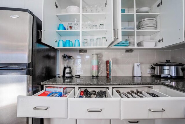 kitchen featuring decorative backsplash, white cabinetry, and stainless steel refrigerator