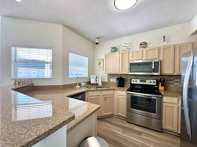 kitchen with light brown cabinets, stainless steel appliances, light hardwood / wood-style flooring, and sink