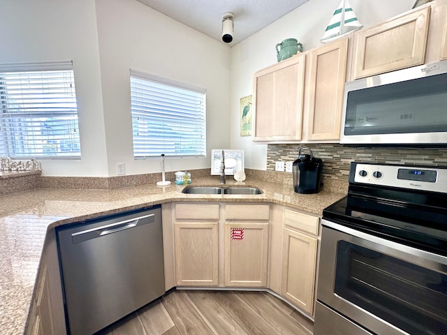 kitchen with a wealth of natural light, sink, light wood-type flooring, and appliances with stainless steel finishes