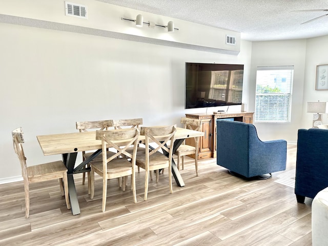 dining space with a textured ceiling, light hardwood / wood-style flooring, and ceiling fan