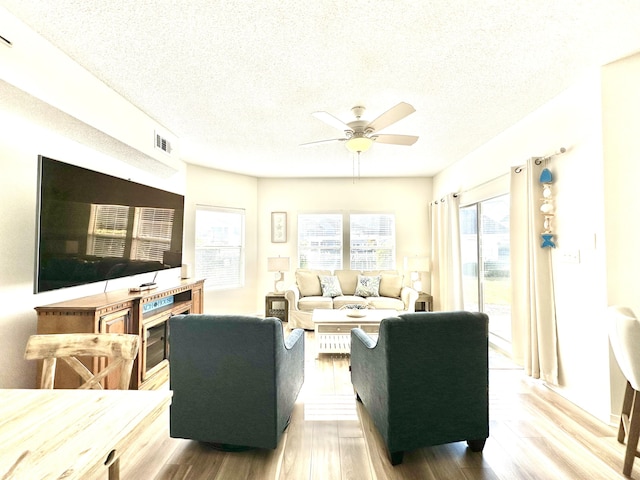 living room featuring ceiling fan, a textured ceiling, and hardwood / wood-style flooring