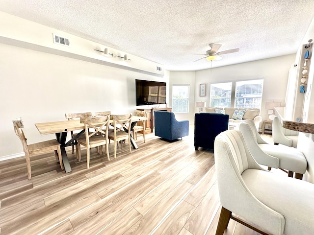 living room featuring ceiling fan, a textured ceiling, and hardwood / wood-style flooring