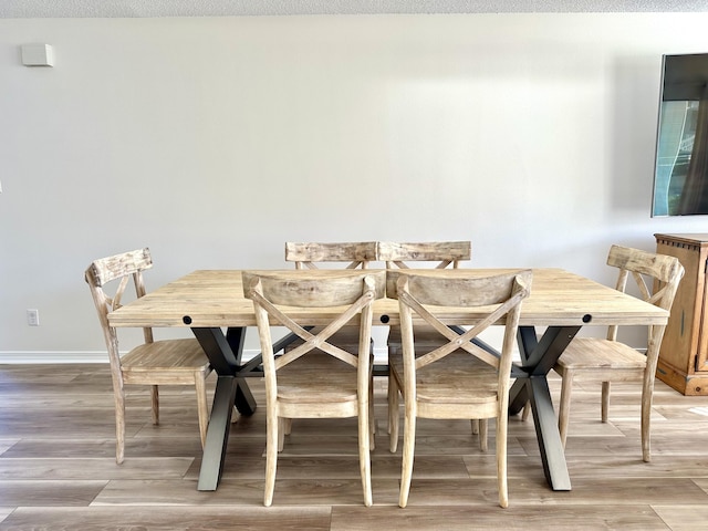 dining space with hardwood / wood-style flooring and a textured ceiling