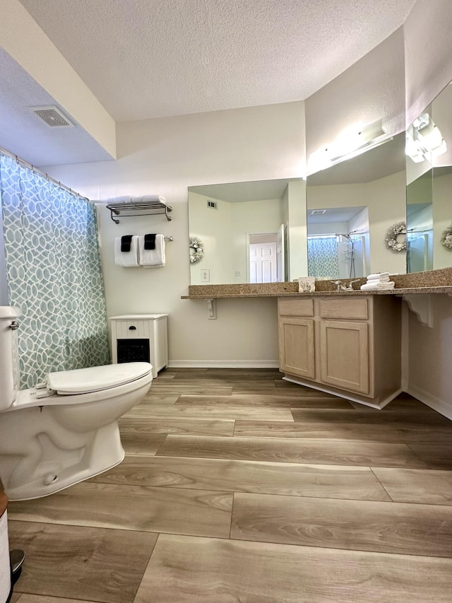 bathroom featuring hardwood / wood-style floors, vanity, toilet, and a textured ceiling