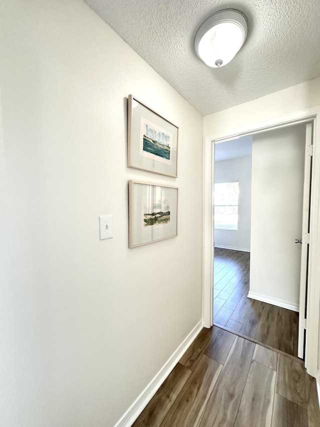 hall featuring wood-type flooring and a textured ceiling